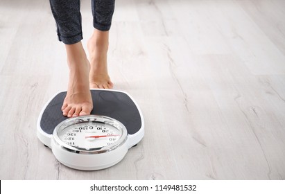 Mujer midiendo su peso usando básculas en el suelo
