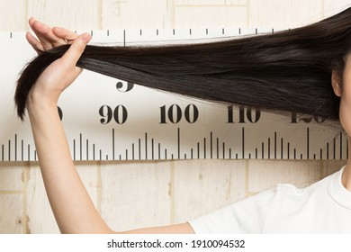 The Woman Is Measuring The Length Of Her Hair.