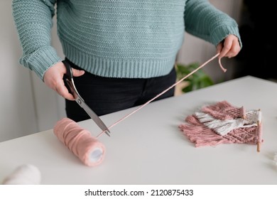 Woman Measuring Piece Of The Rope From The Coil For Macrame Weaving With Big Scissors. Handmade Macrame Belt In Work Process. Female Hobby. Wall Hanging Decor. Diy