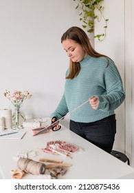 Woman Measuring Piece Of The Rope From The Coil For Macrame Weaving With Big Scissors. Handmade Macrame Belt In Work Process. Female Hobby. Wall Hanging Decor. Diy