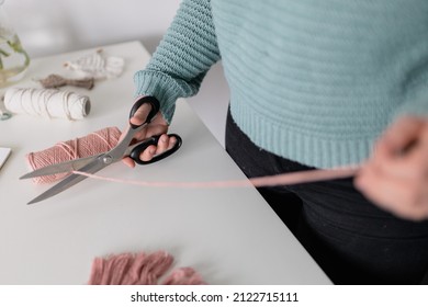 Woman Measuring Piece Of The Rope From The Coil For Macrame Weaving With Big Scissors. Handmade Macrame Belt In Work Process. Female Hobby. Wall Hanging Decor. Diy