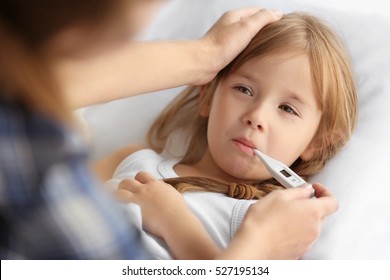 Woman measuring temperature of small sick girl
