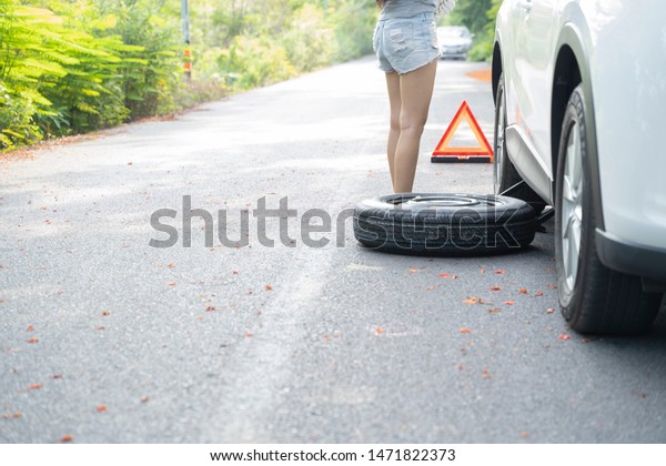 Woman mechanic changing tire. with a spare tire\
to change.