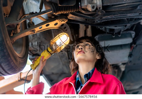 Woman Mechanic\
Examining Under the Car at the Repair Garage. Asian young female\
checking and maintenance the car.\
