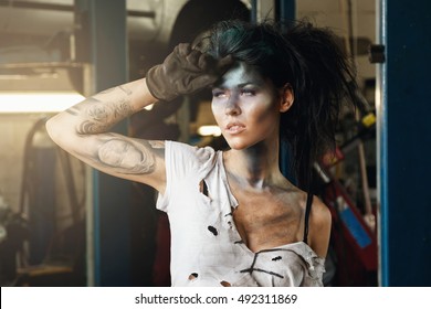 Woman Mechanic In The Garage With Artistic Makeup On Her Face Stylized Like A Dirty Spot