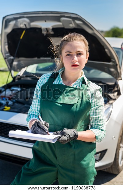 Woman\
mechanic making some notes about broken\
car