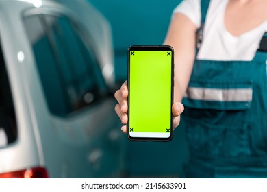 Woman Mechanic In Overall Shows A Smartphone With Green Chroma Key. Mock Up. Close Up. The Concept Of Women's Equality.