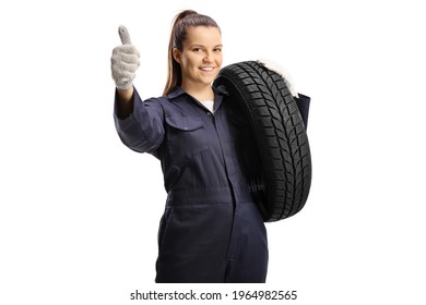 Woman mechanic worker carrying a car tire and gesturing a thumb up sign isolated on white background - Powered by Shutterstock