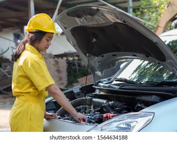 The Woman In The Mechanic's Uniform Is Opening The Radiator Cap Of The Engine To Check The Water Level, In Accordance With Engine Maintenance Standards