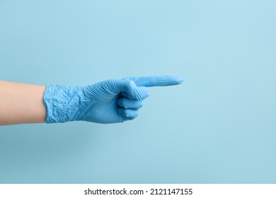 Woman In Medical Glove Pointing At Something On Blue Background