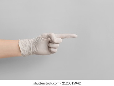 Woman In Medical Glove Pointing At Something On Light Background