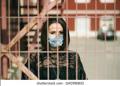 
Woman In Medical Mask Behind Bars During Coronavirus Epidemic. Symbol Of Digital Total Control, 
Fear, Lack Of Freedom, Prison And New World Order. Conceptual Photo On Human Rights During COVID-19