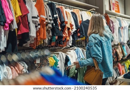 Woman in medical mask choosing clothes in outlet store.