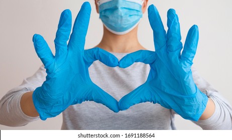 Женщина с медицинской маской и руками в латексной перчатке показывает символ сердца. Доктор для сердца. Любовь к поджелудочной железе. Люблю наших медицинских работников.