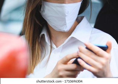 Woman In Medical Mask Holding Mobile Phone In Car