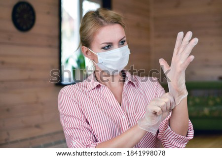 woman in medical mask puts on gloves. Medical person with a mask on face. observe virus protection measures. stay at home. mandatory wearing of sterile gloves.