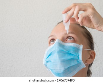 Woman In A Medical Mask Using Eye Drops. Prevention Of Viral Infections.