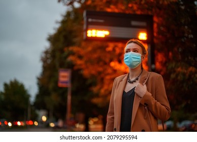 Woman In Medical Mask Is Waiting For Bus At Bus Stop.