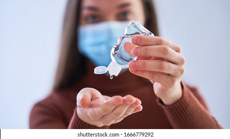 Frau in medizinischer Schutzmaske mit einem antibakteriellen Antiseptikum-Handgel zur Händedesinfektion und -Reinigung während des Ausbruchs des Grippevirus, der Koronavirus-Epidemie und Infektionskrankheiten