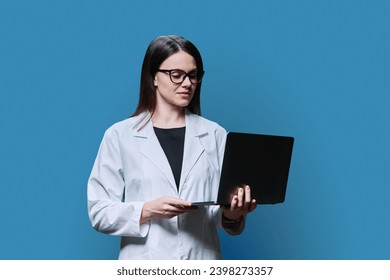 Woman medical scientist, pharmacist in white coat using laptop on blue background - Powered by Shutterstock