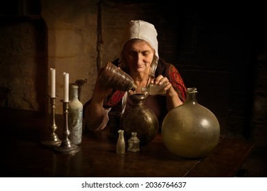 Woman In Medieval Outfit Working As An Alchemist Or Witch In The Kitchen Of A French Medieval Castle - With Property Release