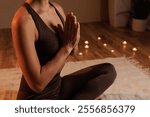 woman meditating with folded palms in a warm cozy atmosphere