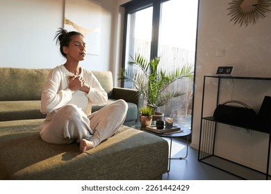 Woman meditating at home with eyes closed 