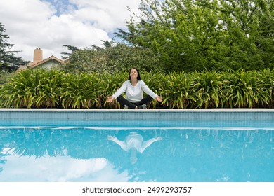 A woman meditating outside by the edge of the pool - Powered by Shutterstock