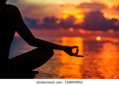 Woman meditating, relaxing in yoga pose at sunset, zen meditation. Silhouette in lotus pose. Mind body spirit concept - Powered by Shutterstock