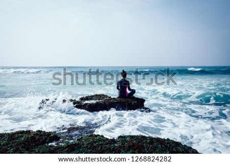 Woman meditation at the seaside croal cliff edge facing the coming sea waves