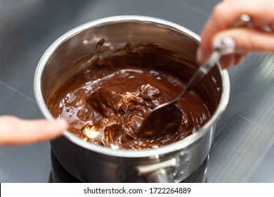 Woman melting chocolate in a pan and mix it with butter, close-up. Cooking at home, homemade sweet food.