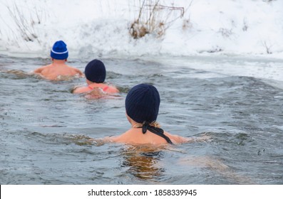 Woman And Men Extreme Winter Swimming, In Winter In Frost Swim In Ice Water