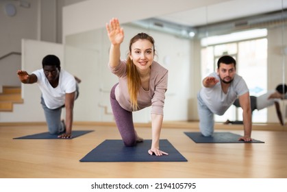 Woman And Men Practising Bird Dog Exercise Together During Fitness Class In Studio.