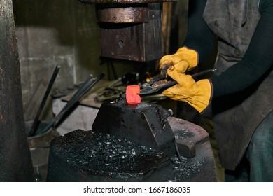 woman metal artist processes a red hot workpiece with a power hammer in a workshop - Powered by Shutterstock