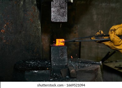 woman metal artist processes a red hot workpiece with a power hammer in a workshop - Powered by Shutterstock