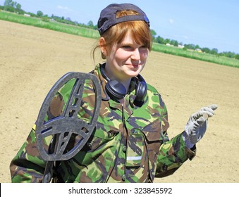 Woman With A Metal Detector Searching In A Field. Old Coin In Hand