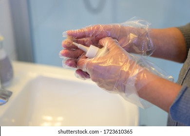 Woman Mixing A Bottle Of Hair Dye In A Bathroom As She Prepares To Apply Coloring To Her Hair With Gloved Hands In Close Up