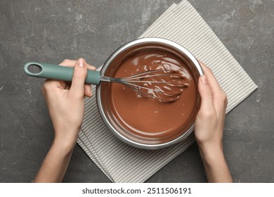 Woman mixing chocolate dough with whisk at grey table, top view - Powered by Shutterstock