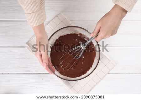 Woman mixing delicious chocolate cream with whisk at white wooden table, top view
