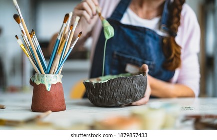 Woman mixing paint with brush inside ceramic bowl in workshop studio - Artisan work and creative craft concept - Focus on bowl - Powered by Shutterstock