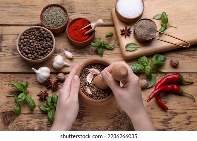 Woman mixing peppercorns with garlic in mortar at wooden table, top view - Powered by Shutterstock