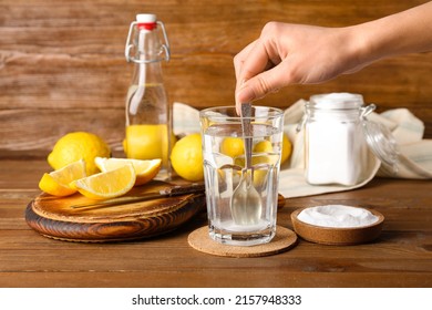 Woman Mixing Water With Baking Soda On Wooden Background