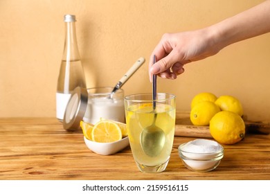 Woman Mixing Water With Baking Soda On Wooden Table