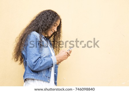 Similar – Serious black woman with afro hair looking at her smart phone outdoors.