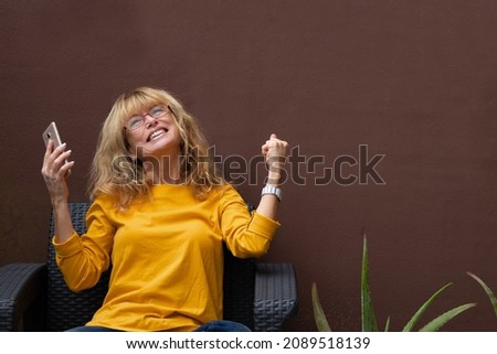 woman with mobile phone celebrating success