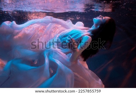 Woman model, ballerina underwater in a fluttering dress. Soft blurred focus. Fantasy