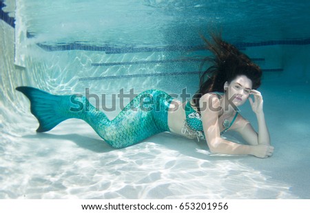 Woman model underwater wearing a green mermaid tail, with matching green stylized shell top.