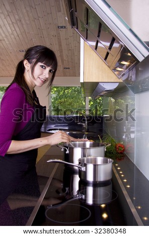 Woman in a modern kitchen stirring in the saucepan