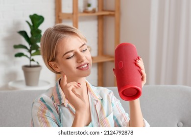 Woman with modern wireless portable speaker in room
