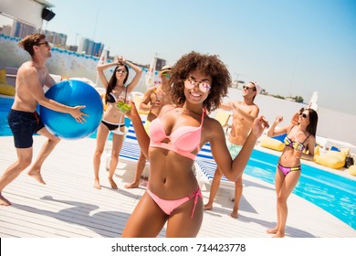 woman with mohito is posing, dancing at the beach pool disco party, enjoying, chilling with friends, they play ball, with huge ribbon blue baloon, at the roof top resort with great view